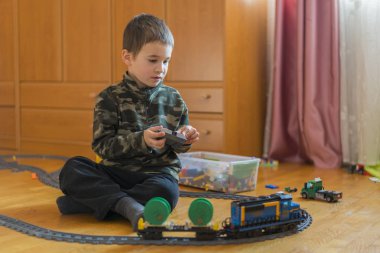Beş yaşında bir çocuk yere demiryolu ile oynuyor. Küçük çocuk yerde yatarken demiryolu ile oynarken.
