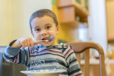 Komik bebek püresi yiyor. Mutlu bebek bebek çocuk kaşık kendisi yiyor.