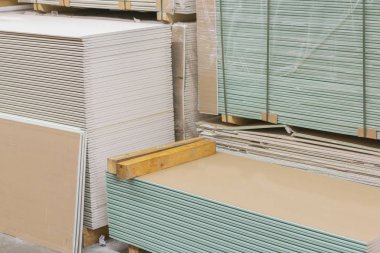 Alçıtaşı alçıtaşı pakette. Alçıtaşı yığını inşaata hazırlanıyor. İnşaat dükkanında alçıpanlı palet. İnşaat malzemeleri. Alçıpan deposu.