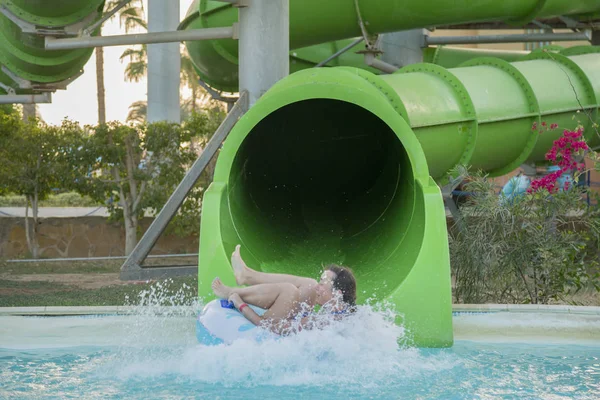 woman going down a water slide. happy woman going down on the rubber ring by the orange slide in the aqua park. Summer Vacation. Weekend on resort.