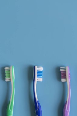 Mavi arka plan üzerinde diş fırçaları. Düz renkli arka plan üzerinde el ile diş fırçası ile kompozisyon yatıyordu, yakın çekim. dikey fotoğraf.