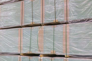 Alçıtaşı alçıtaşı pakette. Alçıtaşı yığını inşaata hazırlanıyor. İnşaat dükkanında alçıpanlı palet. İnşaat malzemeleri. Alçıpan deposu.