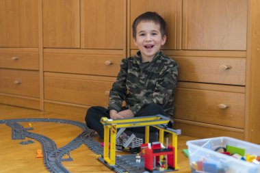 Küçük çocuk bir oyuncak tren ile oynuyor. Yerde yatarken demiryolu ile oynarken küçük çocuk. Neşeli duygular.