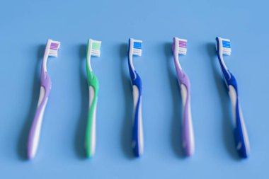 Mavi arka plan üzerinde diş fırçaları. El ile diş fırçası ile düz yatıyordu kompozisyon. Mavi bir arka plan üzerinde çok renkli diş fırçaları. yakın çekim.