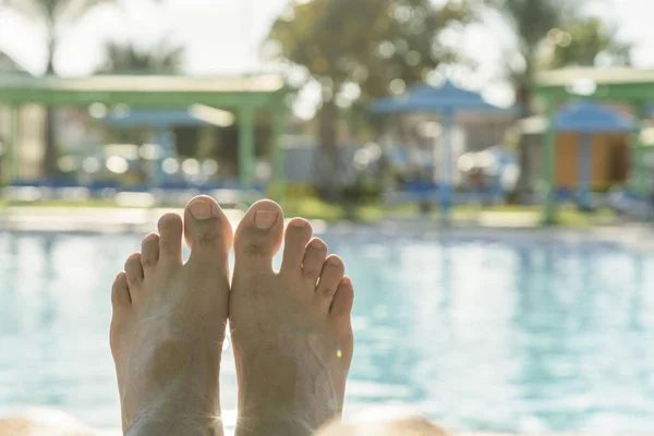 Mannens fötter på bakgrunden av en pool. man avkopplande av poolen, mäns fötter på pool bakgrunden. tonas — Stockfoto
