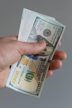 El dolar üzerinde gri bir arka plan ile. dolar para Finans döviz gri arka plan üzerinde elinde. dikey fotoğraf