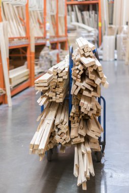 Kereste Amerika'da büyük donanım deposunun içinde raflarda yeni ahşap çubukları yığını. Taze değirmen raf ya da Ahşap ahşap Kafesli döşeme sepeti ve manuel forklift ambarı ile kesme. dikey fotoğraf