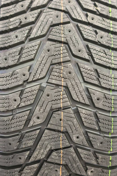 Yakın çekim kış lastiği basmak. Dokulu lastik sırt. Yepyeni modern kış araba lastik parçası. dikey fotoğraf