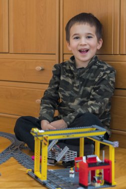 Küçük çocuk bir oyuncak tren ile oynuyor. Yerde yatarken demiryolu ile oynarken küçük çocuk. Neşeli duygular. dikey fotoğraf