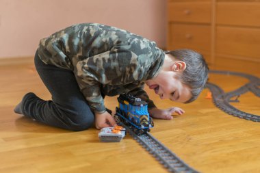 Beş yaşında bir çocuk yere demiryolu ile oynuyor. Küçük çocuk yerde yatarken demiryolu ile oynarken