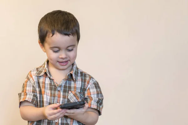 Cep telefonu açık renkli izole tutmak gülümseyen bir küçük çocuk portresi. güzel bir çocuk oyunları smartphone üzerinde oynamak. kopya alanı — Stok fotoğraf