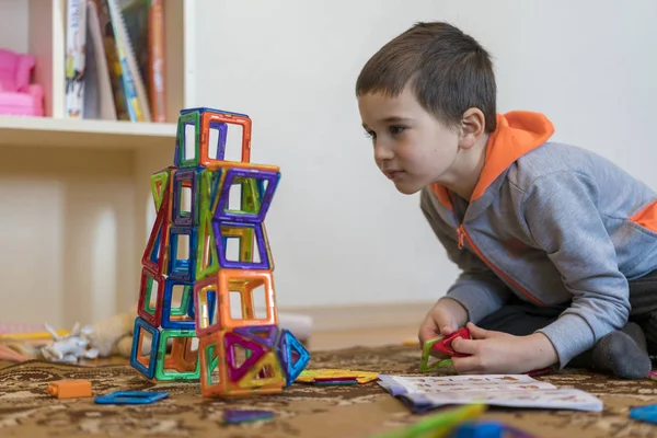 Kleiner lächelnder Junge, der mit magnetischem Konstruktionsspielzeug spielt. Junge spielt intellektuelles Spielzeug — Stockfoto