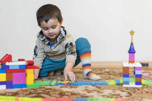 Anak kecil tersenyum bermain dengan mainan konstruktor. Boy bermain mainan intelektual — Stok Foto