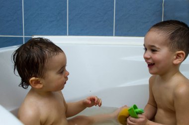 Mutlu kardeşler: alarak su ile birlikte oynayan iki küçük ikiz çocuk banyo küvetinde evde. Çocuk çocuklar eğleniyor tog
