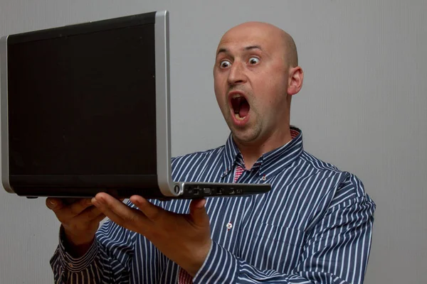 Shocked surprised man looking at laptop computer surprised and amazed with open mouth and big eyes