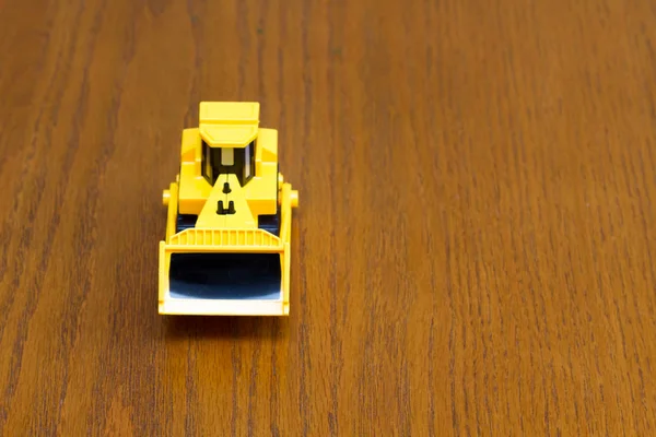 Bulldozer toys with wheels made of plastic isolated on a wood grain texture background. — Stock Photo, Image