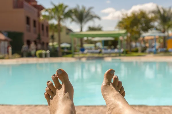 Vackra solbrända ben. Närbild av kvinnliga ben med en pool på bakgrunden. vackra kvinnliga ben på bakgrunden av poolen. Begreppet resten i hotellet — Stockfoto