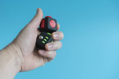 Stres giderici, parmak oyuncak küp. Antistress oyuncak mavi bir arka plan üzerinde. Adam elinde Antistress oyuncak