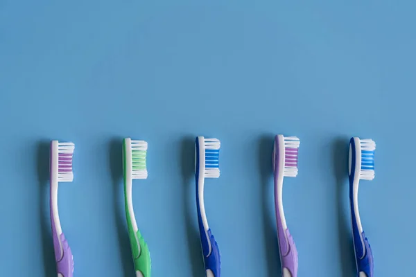 Escovas de dentes no fundo azul. Composição plana com escovas de dentes manuais. Escovas de dentes multicoloridas em um fundo azul. de perto — Fotografia de Stock