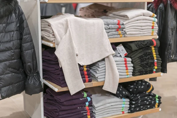 Bonitas pilas de ropa doblada en los estantes de la tienda. Camisa plegable de color En una tienda de ropa ordenadamente organizada —  Fotos de Stock