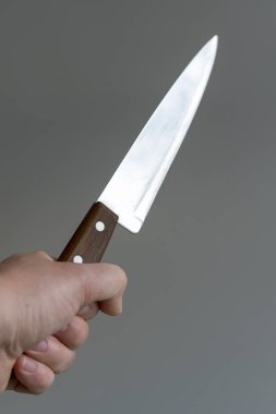 Elini gri arka plan üzerinde bir bıçakla. Şiddet kavramı. El ile bir bıçak bir gangster. dikey fotoğraf.