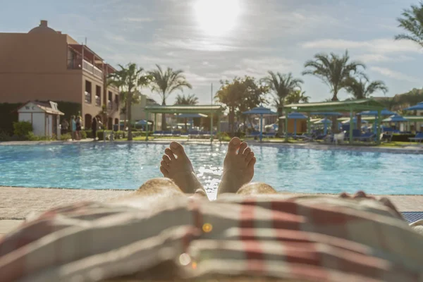 Man\'s feet on the background of a swimming pool. man relaxing by the pool, men\'s feet on the pool background. toned.