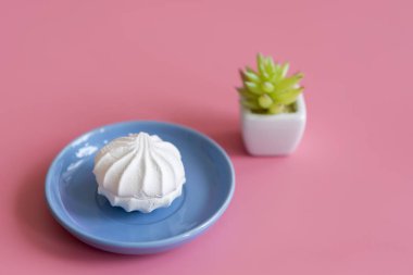 Mavi plaka pembe bir arka plan üzerinde beyaz pasta.