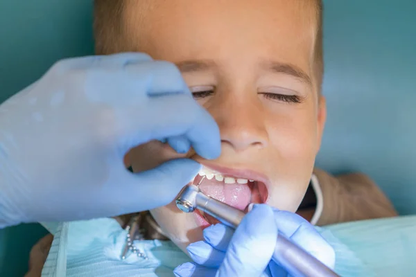 歯科医院で歯科医の受付で小さな男の子。子供の歯科、小児歯科。女性口科医は、学齢期の少年の歯を扱っています。口腔の健康と衛生 — ストック写真