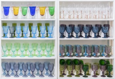 Hediyelik eşya dükkanında rafta renkli gözlük ve vazolar. şarap bardakları büyük bir süpermarkette raflarda durmak.