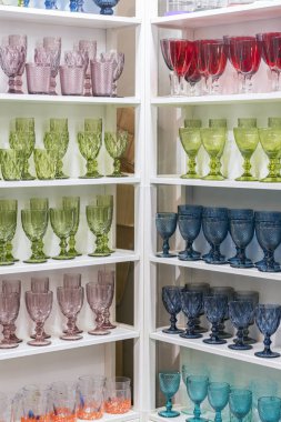 Hediyelik eşya dükkanında rafta renkli gözlük ve vazolar. şarap bardakları büyük bir süpermarkette raflarda duruyor. dikey fotoğraf.