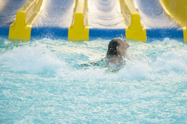 Schönes Mädchen, das eine Wasserrutsche reitet. Glückliche Frau, die an der orangefarbenen Rutsche im Aquapark auf den Gummiring steigt. Sommerferien. Wochenende am Urlaubsort — Stockfoto