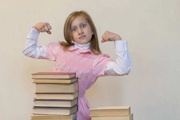 Concept The power of knowledge. A girl with a pile of books shows her strength. Education concept. copy space — Stock Photo, Image