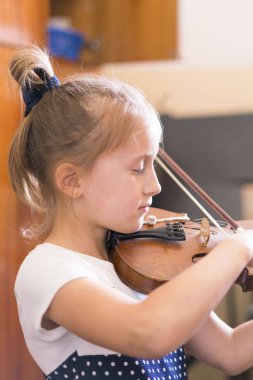 Çocuk, müzik sınıfında keman çalan küçük kız. dikey fotoğraf
