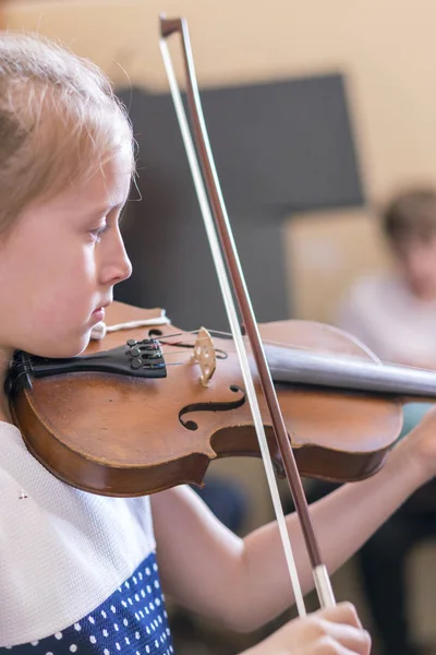 Gyermek, kislány játszik hegedű beltérben zenei osztályban. vertikális fénykép — Stock Fotó