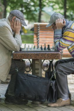 Aktif emekli insanlar, eski arkadaşlar ve serbest zaman, iki yaşlılar eğlenmek ve parkta satranç oyunu oynuyor. Yaşlı adamlar parkta satranç oynuyor. dikey fotoğraf