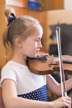 Çocuk, müzik sınıfında keman çalan küçük kız. dikey fotoğraf