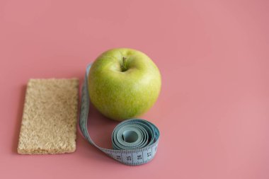 Diyet kavramı yeşil elma ve pembe arka planda bel hattı
