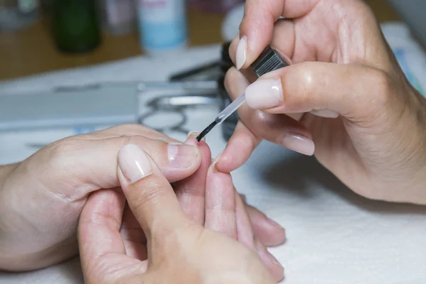 Mujer mano en el tratamiento de manicura con cuchillo de cutícula en el salón de belleza. aplicar un pincel sobre las uñas acrílicas en el salón — Foto de Stock