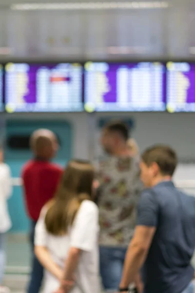 Туристы стоят перед информационной доской в интерьере аэропорта. Размытие изображения людей, ожидающих перед аэропортом Прибытие и Отъезд таблицу времени. вертикальное фото — стоковое фото