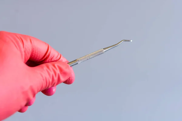 dentist hand in glove holding dental tool