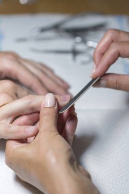 Tırnak güzellik salonunda manikür için üst görünüm manikürcü parlatma işaret parmağı. Manikür sürecinin adımı. Güzellik salonunda manikür. Kostümcü çivilerine seçici bir odaklanma. dikey fotoğraf