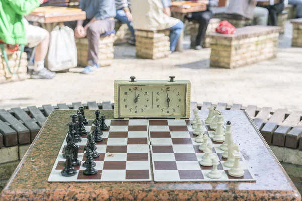 Schachbrett mit Figuren und Uhr auf Holztisch in Verbindung mit dem Schachturnier. Schachturnier mit Schachuhr auf Holztisch — Stockfoto