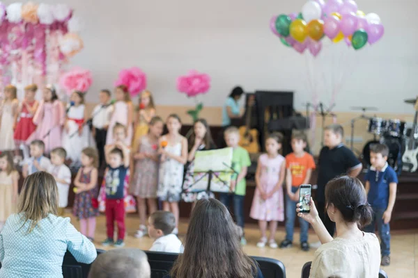 Festa infantil na escola primária. As crianças pequenas no palco no jardim de infância aparecem em pais dianteiros. turva — Fotografia de Stock