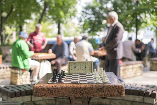 Chess board with pieces and clock on wooden desk In connection with the chess tournament. Chess tournament with chess clock on wooden table