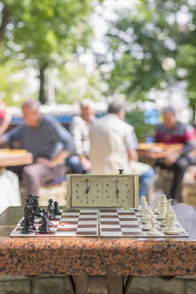 Chess board with pieces and clock on wooden desk In connection with the chess tournament. Chess tournament with chess clock on wooden table. vertical photo