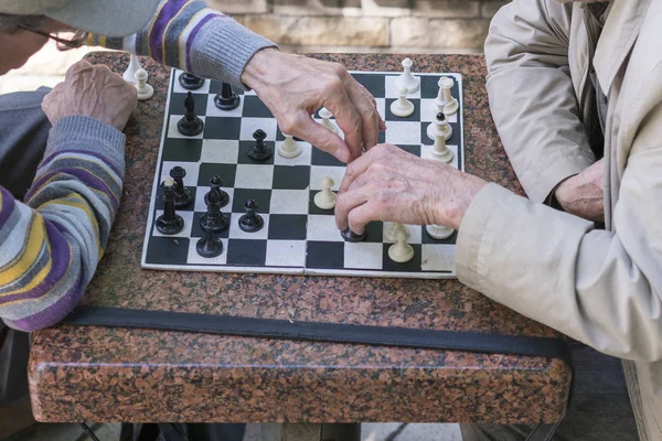 Active retired people, old friends and free time, two seniors having fun and playing chess game at park. Old men are playing chess in a park