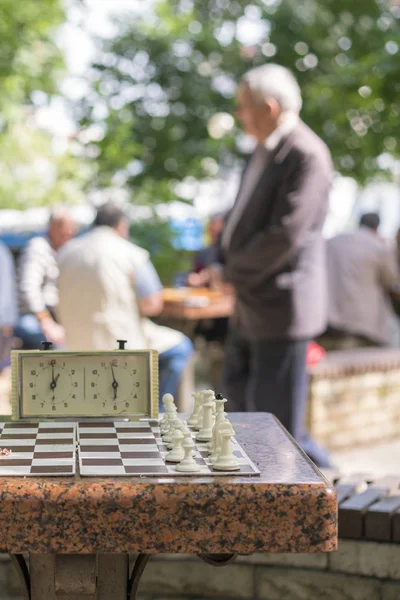Szachownica z kawałkami i zegar na drewnianym biurku w związku z turnieju szachowego. Turniej Szachowy z zegarem szachowym na drewnianym stole. Zdjęcie pionowe — Zdjęcie stockowe
