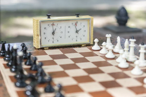 Schack bräde med lappar och klocka på trä skriv bord i anslutning med schackturneringen. Schackturnering med schack tar tid på trä bordlägger — Stockfoto