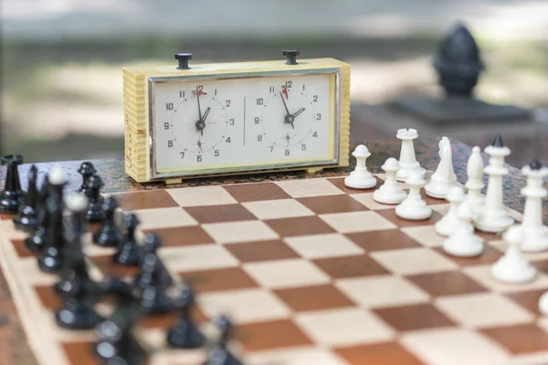 Schachbrett mit Figuren und Uhr auf Holztisch in Verbindung mit dem Schachturnier. Schachturnier mit Schachuhr auf Holztisch — Stockfoto