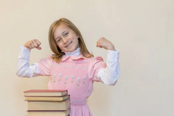 Concepto El poder del conocimiento. Una chica con un montón de libros muestra su fuerza. Concepto educativo. espacio de copia —  Fotos de Stock
